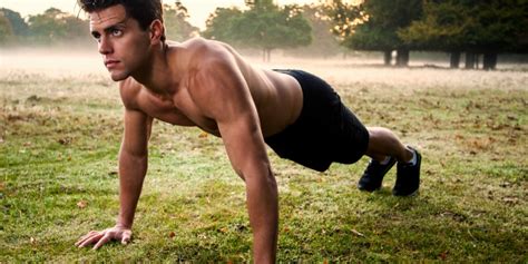 Foto stock che ritrae un ragazzo a petto nudo in posizione di plank sulle mani, su un prato con una leggera nebbia in lontananza